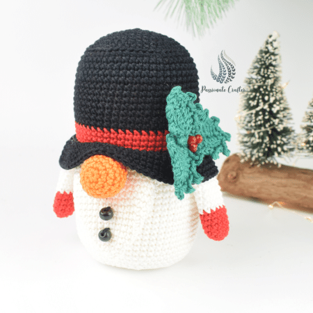 Free crochet Snowman gnome pattern for Christmas home decorations with green holy leaves and red berries on the hat.